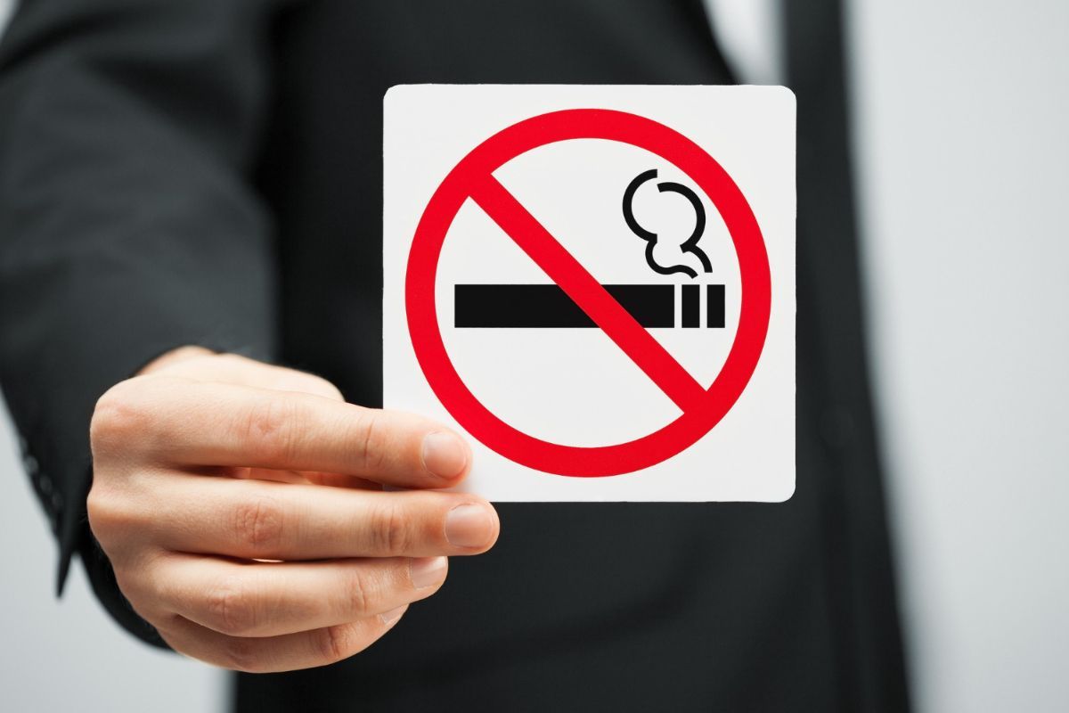 Una mano sostiene un cartel de prohibido fumar