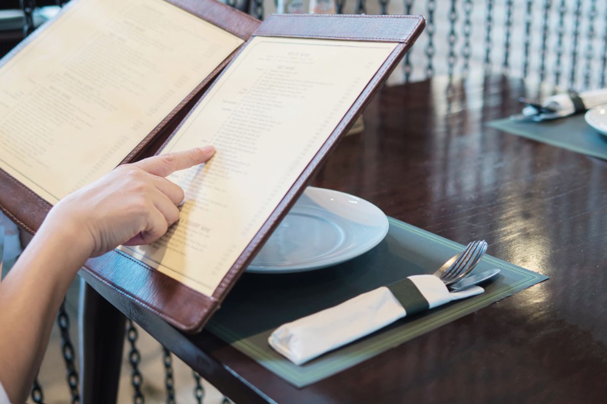 Las manos de una clienta de un restaurante sostienen una carta abierta
