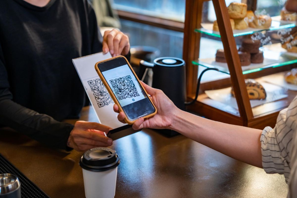  Una clienta pone la cámara sobre un QR para escanearlo y pagar