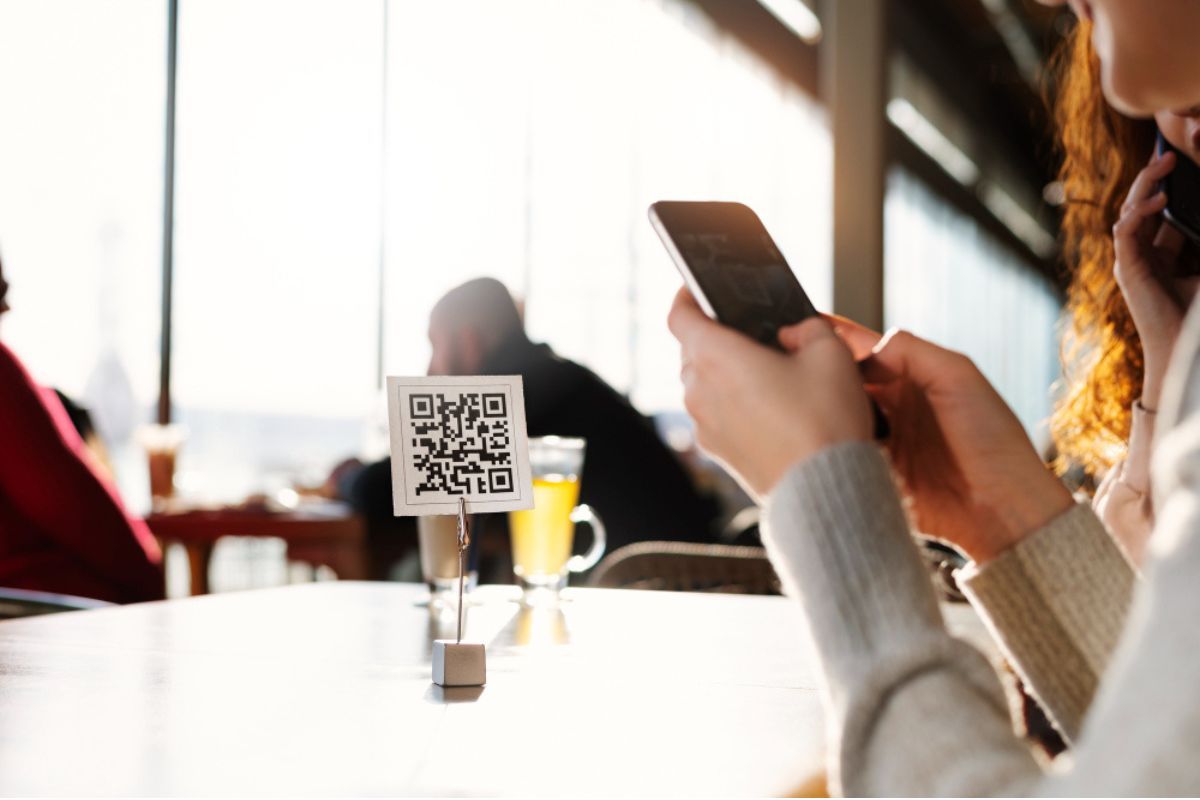 Una clienta de restaurante consulta un código QR con su teléfono móvil