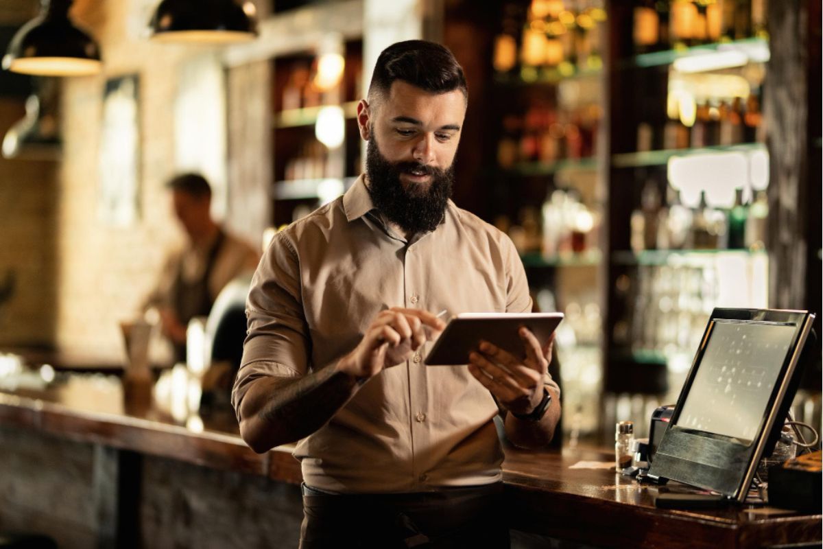 El hostess de un restaurante comprueba la disponibilidad de mesas en una tablet