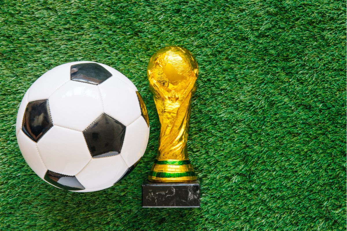 balón de fútbol y trofeo del Mundial sobre césped